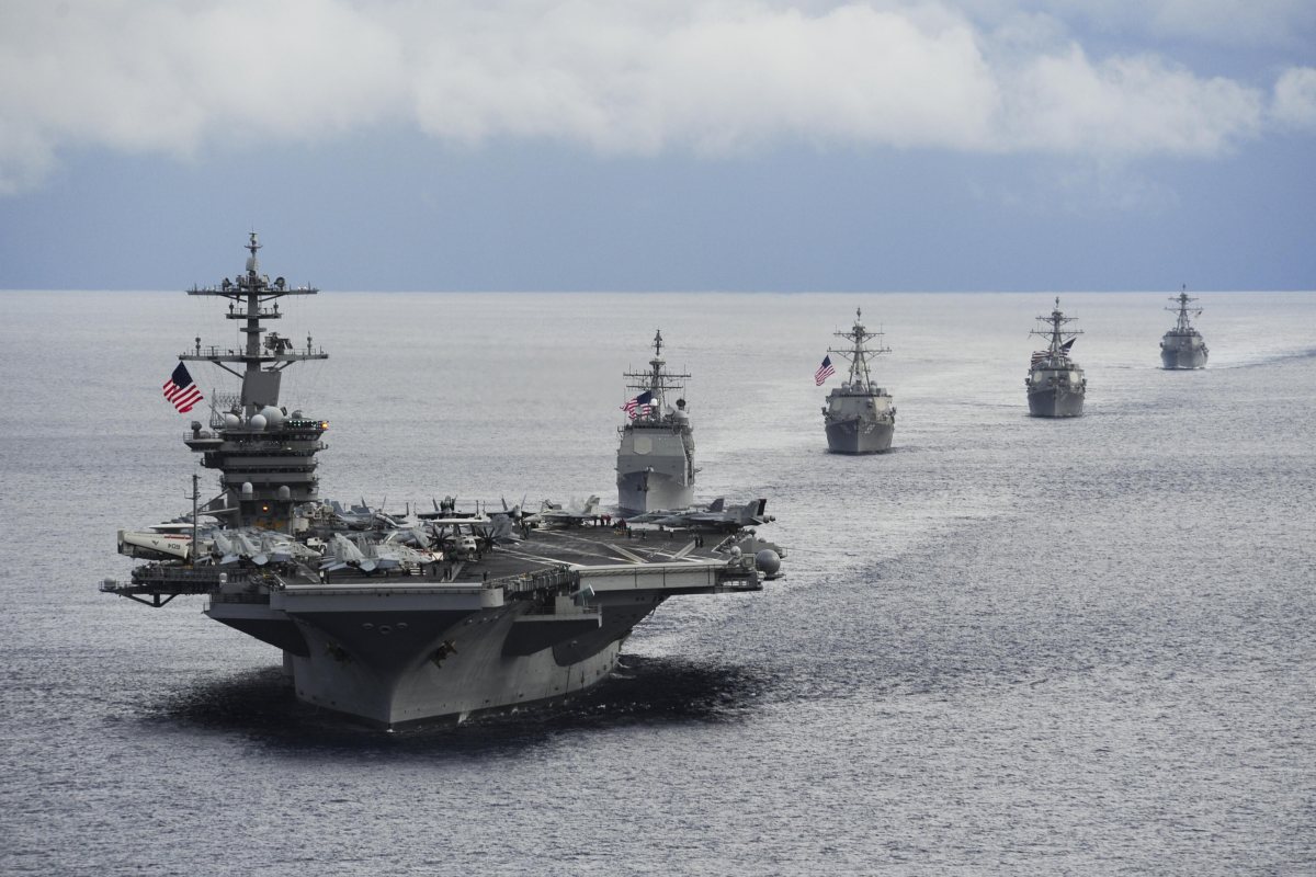 Американският самолетоносач USS Theodore Roosevelt (CVN 71) по време на маневри в Атлантическия океан на фона на изгряващото слънце.